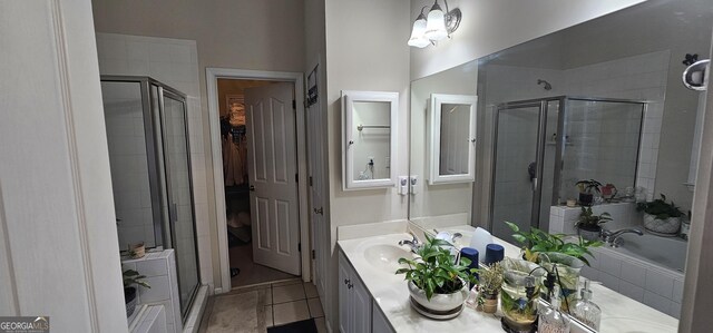 bathroom featuring a spacious closet, a sink, a stall shower, double vanity, and tile patterned floors