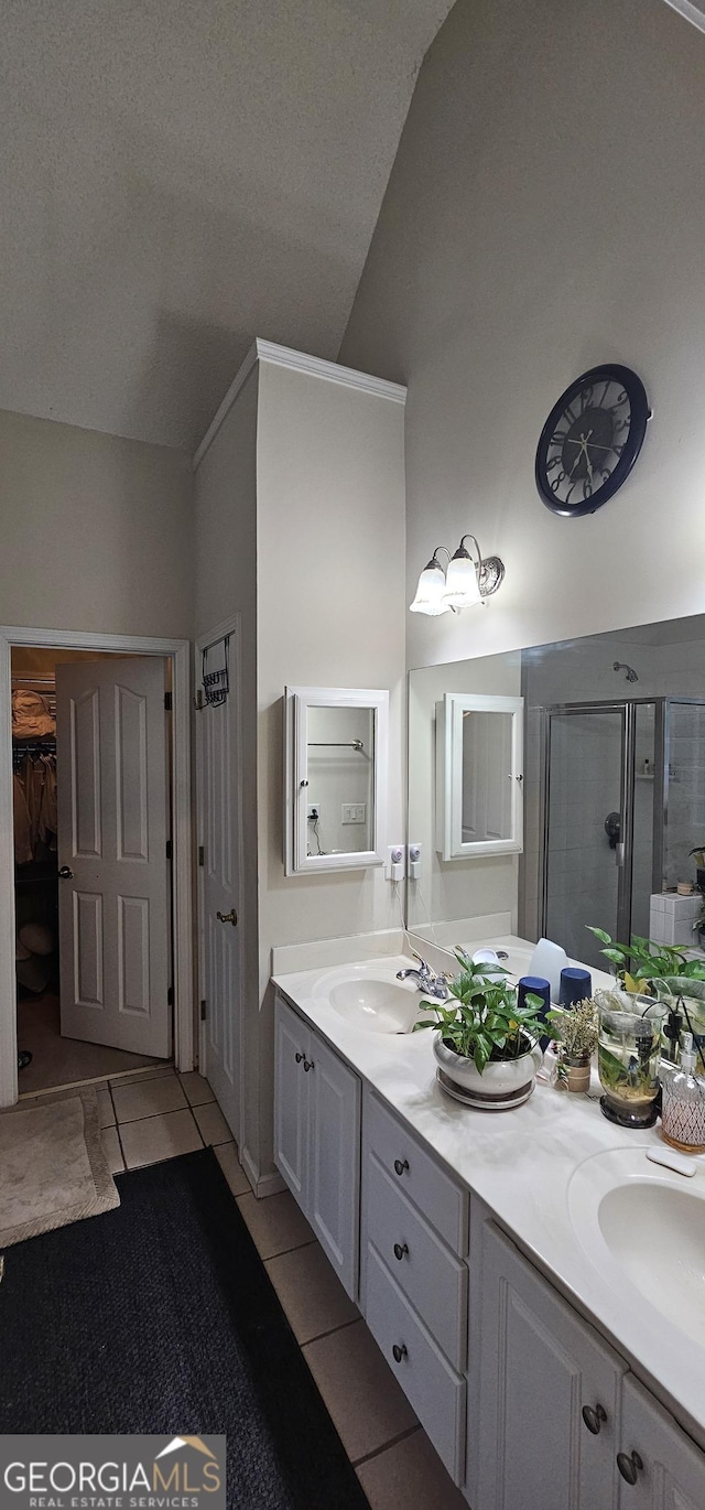 bathroom with tile patterned floors, double vanity, a sink, and a stall shower