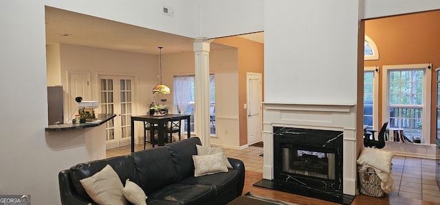 tiled living room featuring visible vents, decorative columns, a multi sided fireplace, and a high ceiling