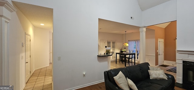 living area featuring visible vents, baseboards, ornate columns, and light tile patterned flooring
