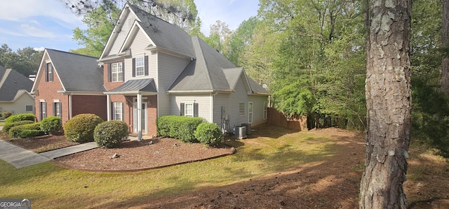view of front of home featuring cooling unit, roof with shingles, a front yard, and brick siding