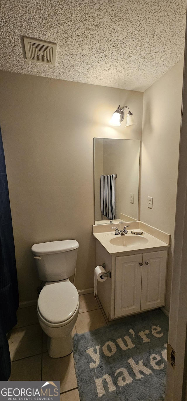 bathroom with a textured ceiling, vanity, tile patterned flooring, visible vents, and toilet
