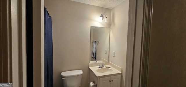 bathroom with toilet, vanity, and a textured ceiling