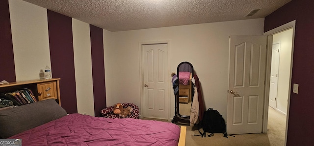 bedroom featuring a textured ceiling, visible vents, and carpet