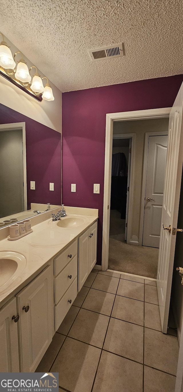 full bath featuring tile patterned flooring, visible vents, a textured ceiling, and a sink