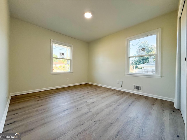 spare room featuring wood finished floors, visible vents, and baseboards
