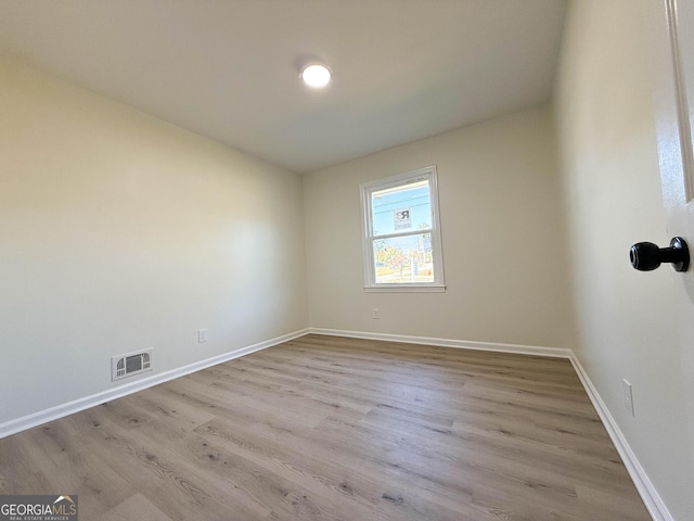 empty room featuring visible vents, baseboards, and wood finished floors