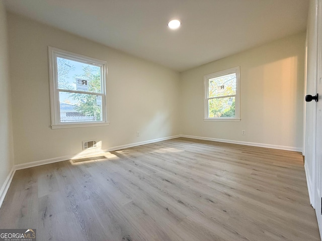 spare room featuring visible vents, baseboards, and wood finished floors