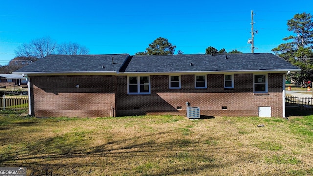 rear view of property with crawl space, a lawn, cooling unit, and fence