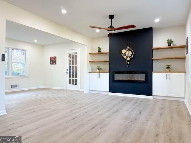 unfurnished living room with visible vents, ceiling fan, a fireplace, and light wood finished floors