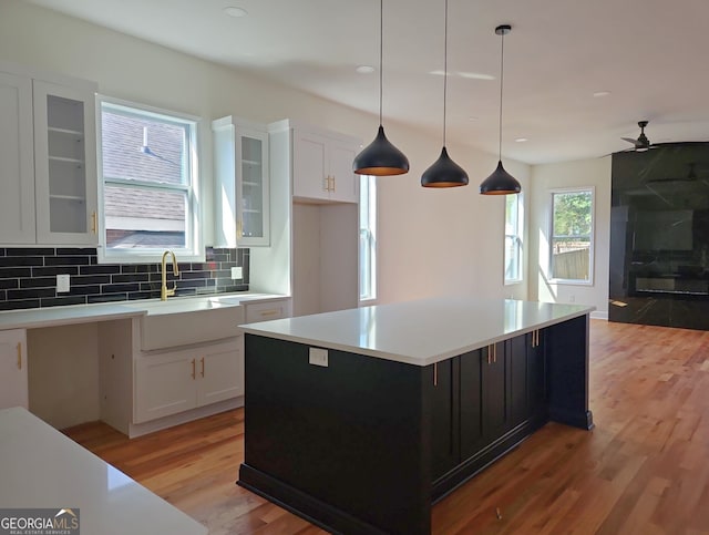 721 Cascade Ave SW, Atlanta, GA 30310 - kitchen with light wood-type flooring, white cabinets, ceiling fan, glass insert cabinets, and decorative backsplash