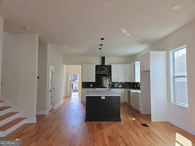 721 Cascade Ave SW, Atlanta, GA 30310 - kitchen featuring wall chimney range hood, a center island, backsplash, light countertops, and light wood-style flooring