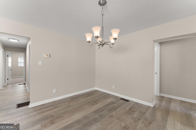 unfurnished dining area featuring baseboards, wood finished floors, and visible vents