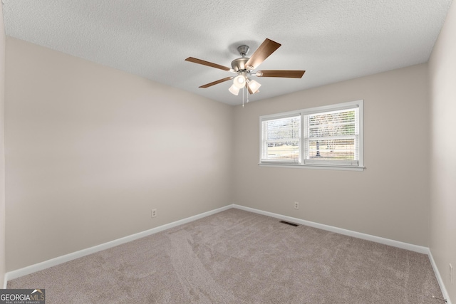 spare room with a textured ceiling, visible vents, baseboards, carpet, and a ceiling fan
