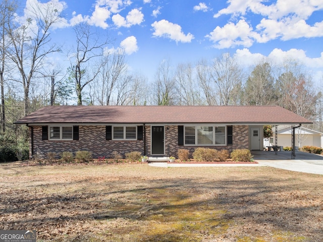 view of front of house featuring brick siding, driveway, a front yard, and a carport