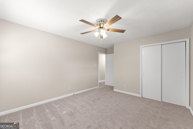 unfurnished bedroom featuring carpet floors, a closet, baseboards, and ceiling fan