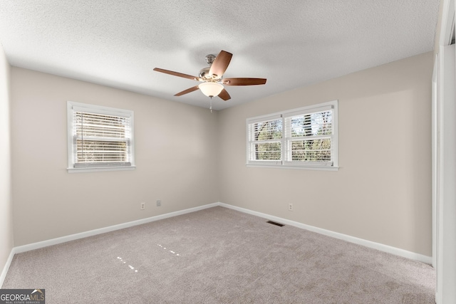 carpeted empty room with ceiling fan, baseboards, and a textured ceiling
