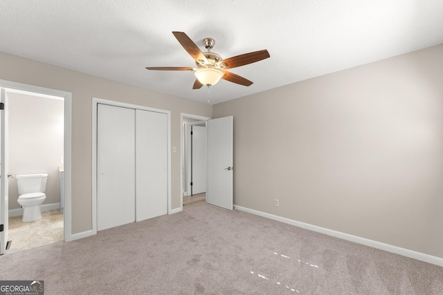 unfurnished bedroom featuring a closet, baseboards, light carpet, and ensuite bathroom