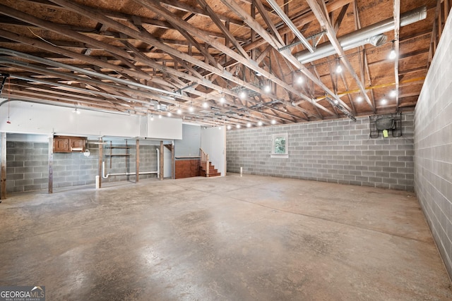below grade area featuring stairs and concrete block wall