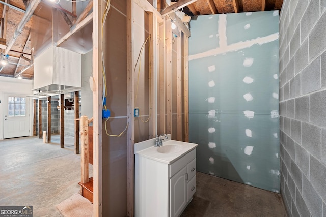 bathroom with concrete block wall, vanity, and concrete floors