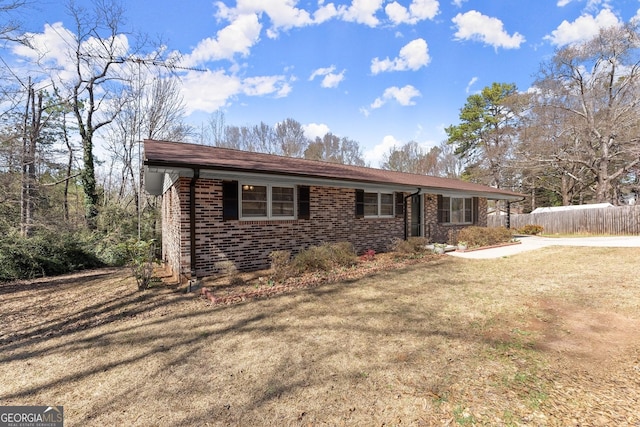 view of front of house with brick siding, a front yard, and fence