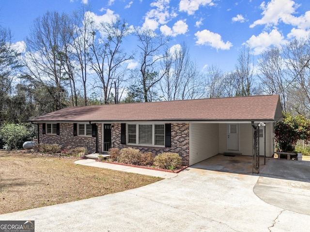 single story home with a shingled roof, an attached carport, and concrete driveway