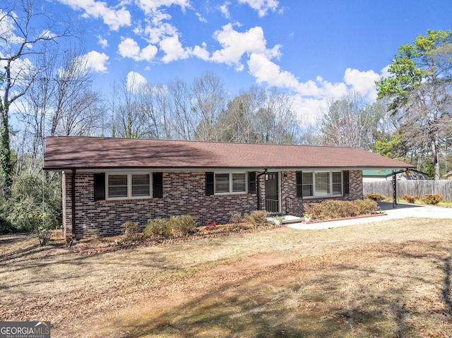 view of front of property featuring concrete driveway, fence, a carport, and brick siding
