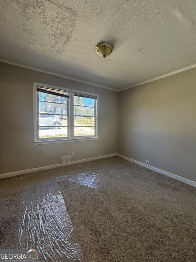 carpeted spare room featuring baseboards, ornamental molding, a textured ceiling, and visible vents