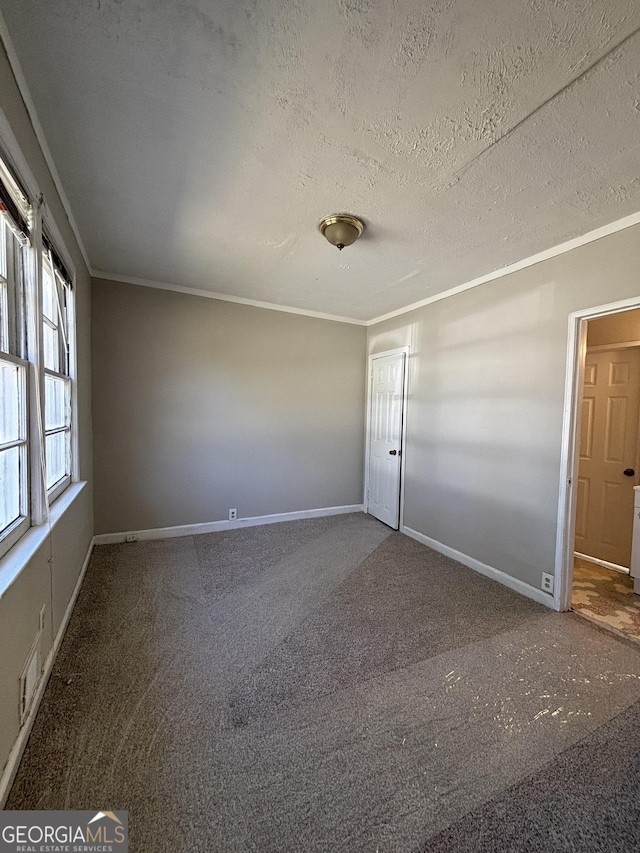 spare room featuring baseboards, carpet floors, a textured ceiling, and crown molding