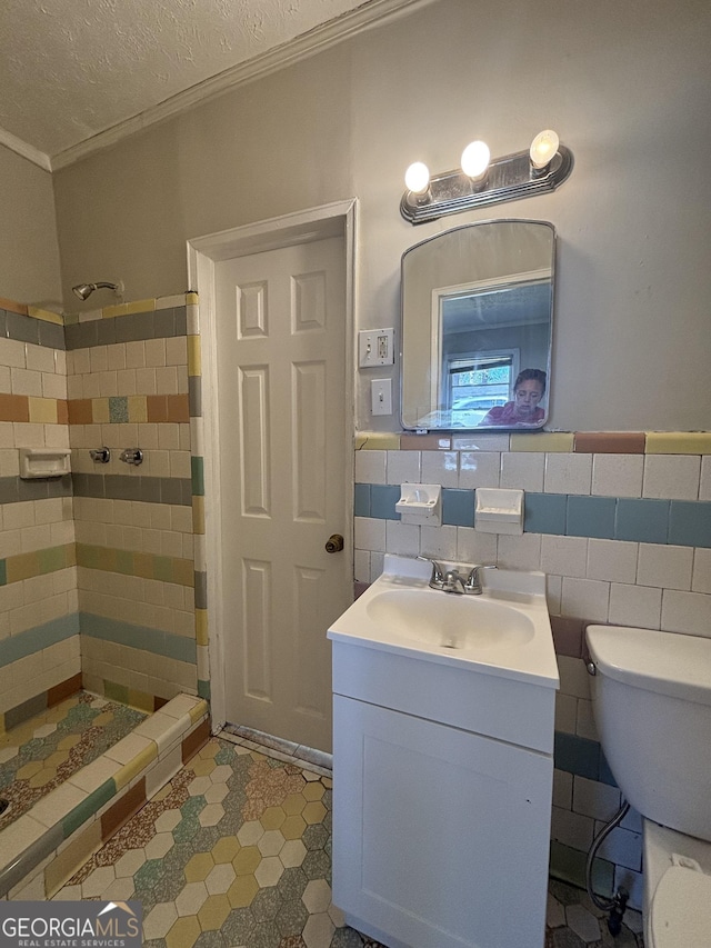 full bath featuring a tile shower, toilet, vanity, and ornamental molding