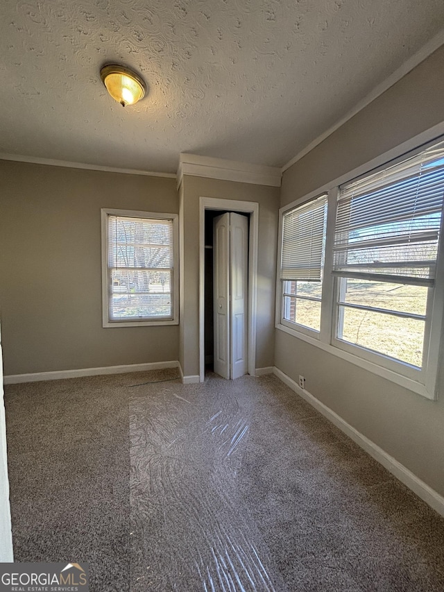 unfurnished bedroom with a closet, crown molding, and multiple windows