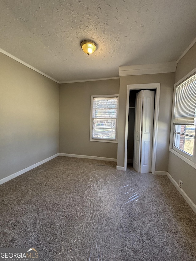 unfurnished bedroom with carpet flooring, a textured ceiling, a closet, and crown molding