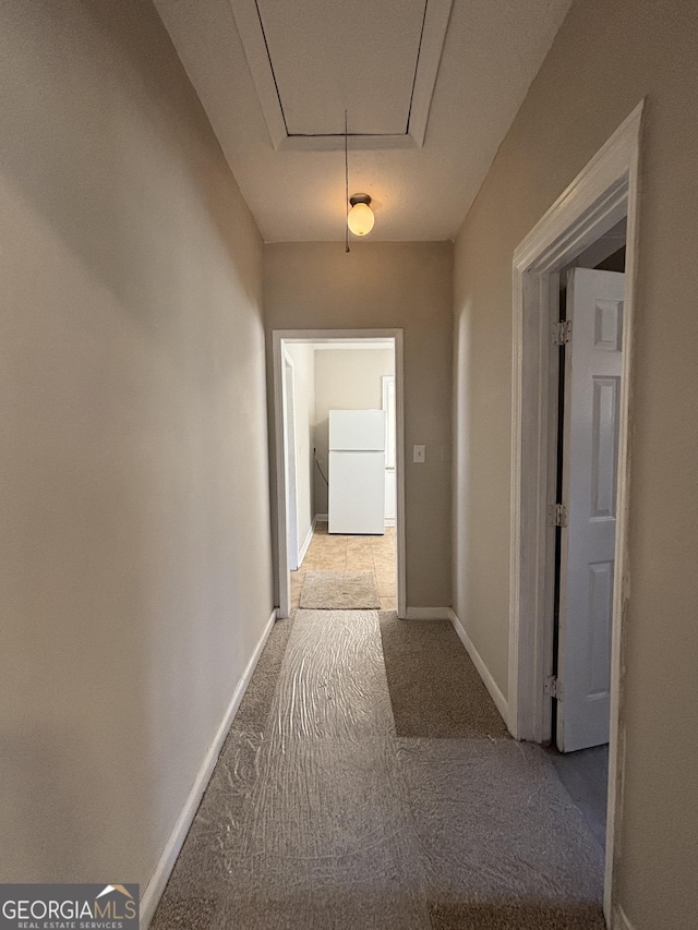 hallway featuring attic access, carpet flooring, and baseboards