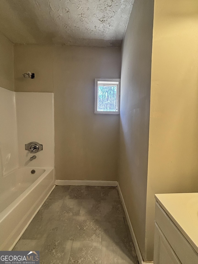 bathroom featuring baseboards, vanity, and bathtub / shower combination