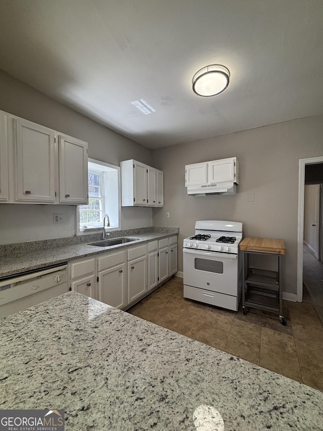 kitchen featuring a sink, white appliances, baseboards, white cabinetry, and light stone countertops