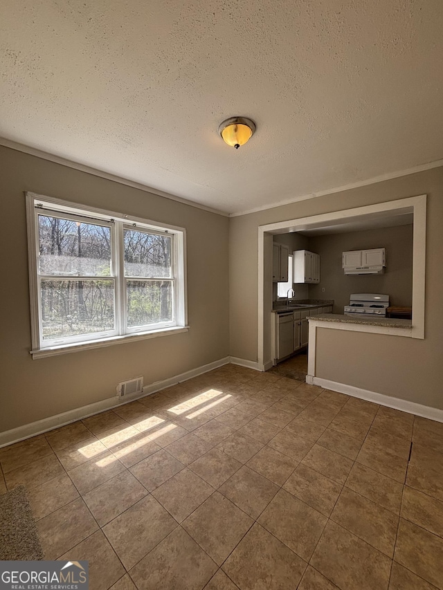 interior space featuring tile patterned flooring, visible vents, ornamental molding, baseboards, and a textured ceiling