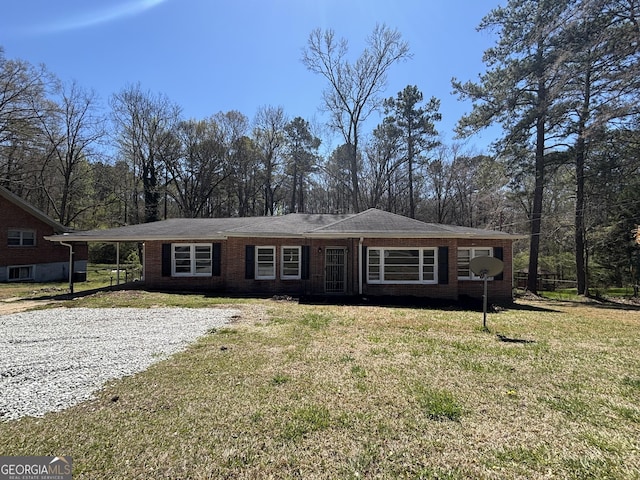 single story home featuring a carport, driveway, a front lawn, and brick siding