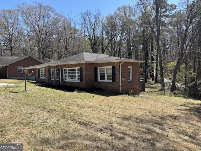 view of side of home with fence, brick siding, and a yard
