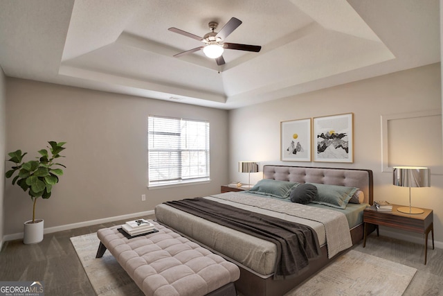 bedroom featuring baseboards, ceiling fan, and a raised ceiling