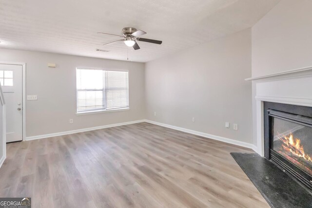 344 Springbottom Ct, Lawrenceville, GA 30046 - unfurnished living room with baseboards, a glass covered fireplace, a ceiling fan, and wood finished floors
