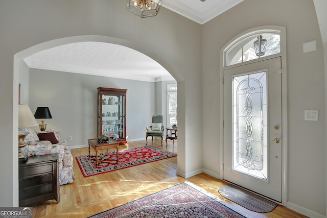 entrance foyer with baseboards, a healthy amount of sunlight, arched walkways, and ornamental molding