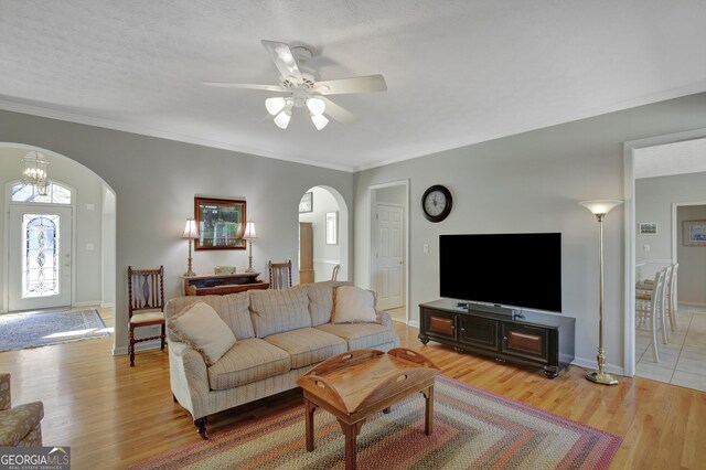 living area with ceiling fan, baseboards, arched walkways, and light wood-style flooring