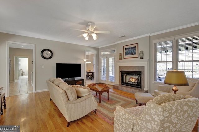 living area with baseboards, visible vents, light wood finished floors, ornamental molding, and ceiling fan