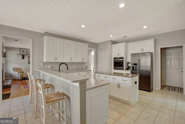 kitchen featuring a kitchen island, appliances with stainless steel finishes, a peninsula, white cabinets, and light tile patterned floors