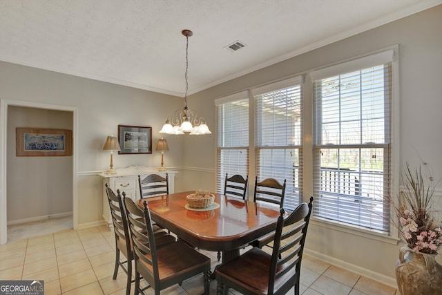 dining area with light tile patterned floors, visible vents, an inviting chandelier, and ornamental molding