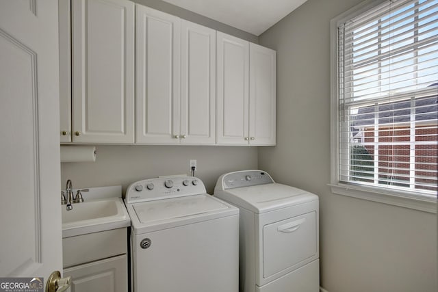 washroom with a sink, cabinet space, and washer and clothes dryer