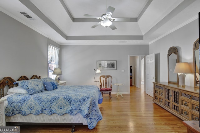 bedroom featuring visible vents, crown molding, baseboards, light wood-type flooring, and a raised ceiling