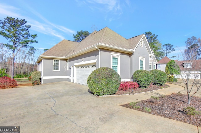 view of home's exterior featuring stucco siding, driveway, roof with shingles, and an attached garage