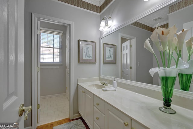 bathroom featuring baseboards, ornamental molding, and vanity