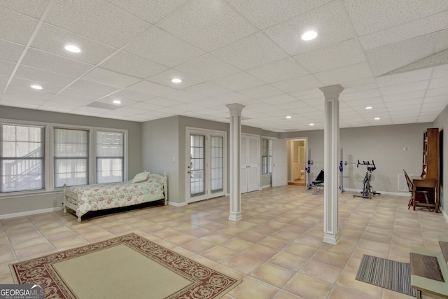 bedroom featuring light tile patterned floors, baseboards, and ornate columns